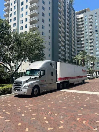 Moving truck parked outside a high-rise apartment building on a sunny day for short distance moving service.