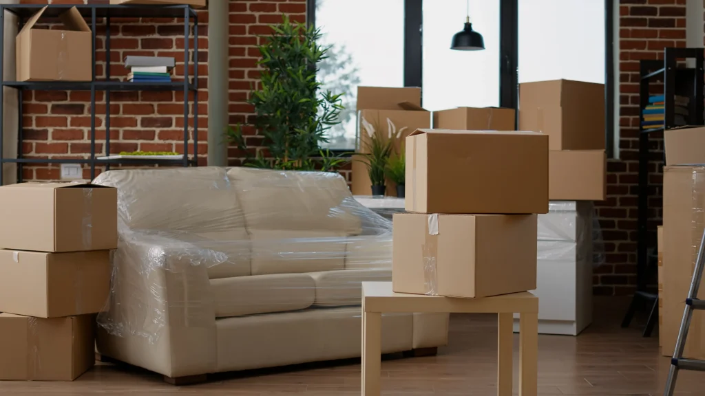 Living room filled with packed cardboard boxes and wrapped furniture prepared for short distance moving.