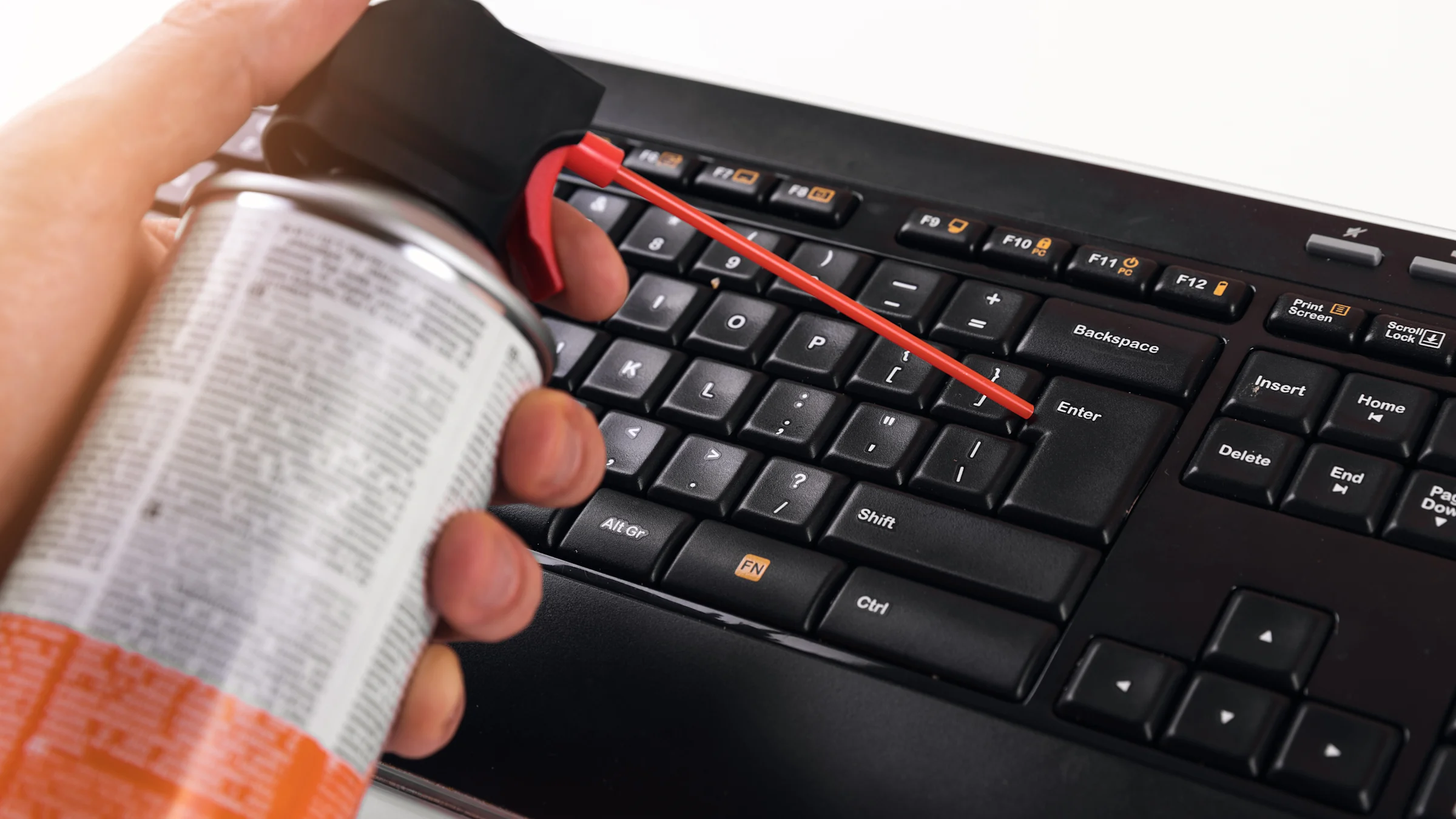 Compressed air being used to clean between the keys of a keyboard