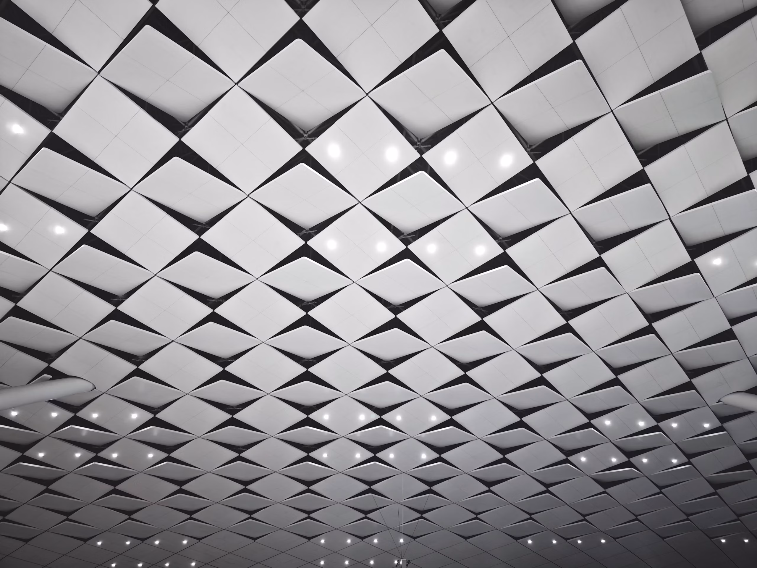 A geometric acoustic ceiling of angled square tiles, the pattern holding true across the full span